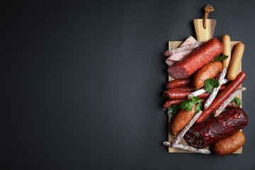 Different types of sausages served on black background, top view. Space for text]