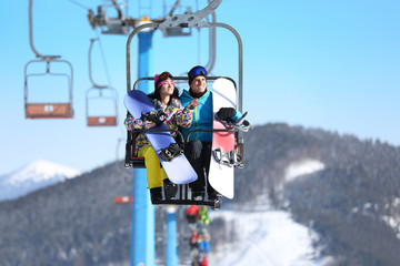 People using chairlift at mountain ski resort. Winter vacation