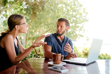 Two partners disputing about business plans while working with laptop in cafe. Coworking and freelance concept.