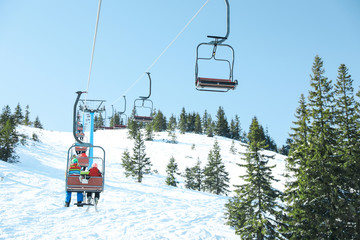 People using chairlift at mountain ski resort. Winter vacation