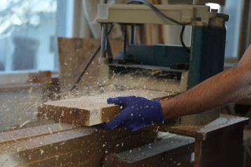 Professional carpenter working with grinding machine in shop, closeup