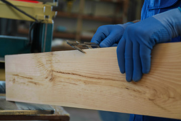 Professional carpenter measuring wooden board with sliding caliper in workshop, closeup