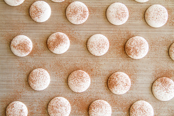 French dessert macaron. The photo of making macaron powdered with cocoa powder. Macaron in process, before baking. Macarons piped on a tray covered with a teflon sheet. Top view.