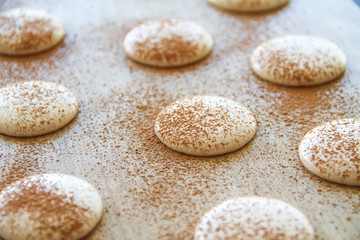 French dessert macaron. The photo of making macaron powdered with cocoa powder. Macaron in process, before baking. Macarons piped on a tray covered with a teflon sheet. Back view.