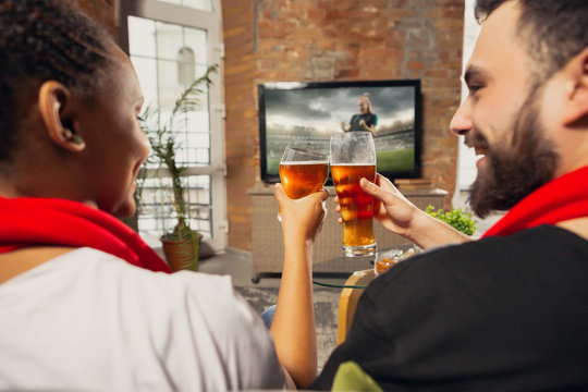 Excited group of people watching football, soccer sport match at home. Multiethnic group of emotional friend, fans cheering for favourite national team, drinking beer. Concept of emotions, support.