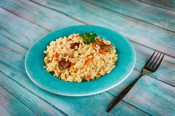 Pilaf with rice , curry spice, carrot and meat on blue plate.