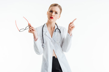 sexy nurse holding glasses and pointing with finger isolated on white