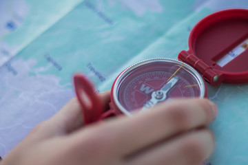Close-up of a woman's hands catching a compass on a map in the countryside