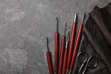 Leather sample and craftsman tools on grey stone background, flat lay. Space for text