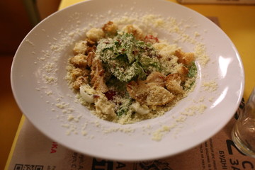  Caesar salad with parmesan and chicken on a white plate in a restaurant