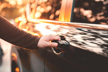 Hand on handle. Close-up of woman hand opening a car door with sunlight effect.