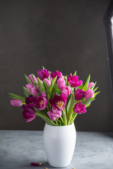 bouquet of tulips in white vase on stone grey background