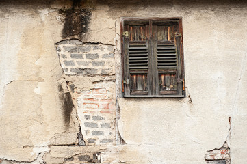 Verwittertes Gebäude mit Backsteinmauer und Fensterladen
