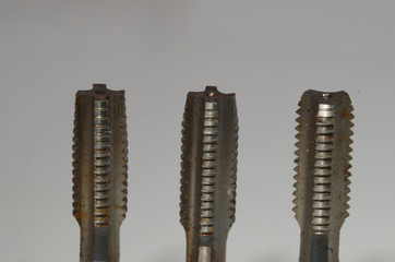Closeup on size M8 thread tap set with taper tap to the left, second tap in the middle, and bottoming tap to the right.