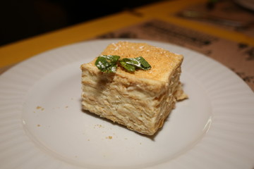 a piece of cake Napoleon lies on a plate in a restaurant, close-up