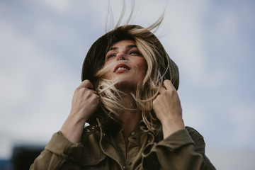 Portrait of young beautiful woman in the hood against the sky