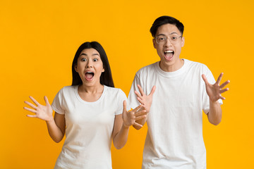 Shocked emotional asian couple on yellow background
