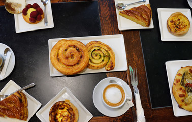 Top view on the table with pies, cakes and pastries, buns, bakery products and coffe during coffee breaks in french cafe