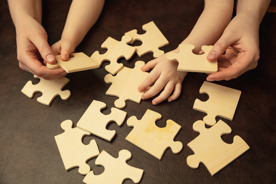 Collecting pazzles, building future. Close up shot of female and kid's hands doing different things together. Family, home, education, childhood, charity concept. Mother and son or daughter, wealth.
