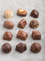 Different chocolate candies on a gray concrete background. side view.