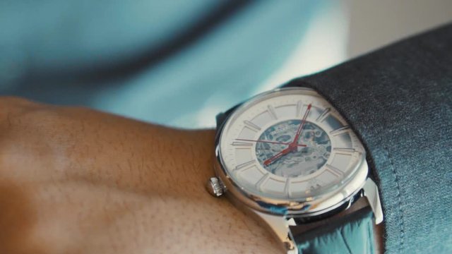 Looking at the clock, a mechanical watch on man's arm. Close-up