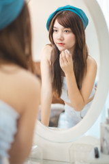 Beautiful Young Asian Woman long hair  with Clean Fresh Skin. Face care, Facial treatment, Cosmetology, beauty and healthy skin and cosmetic ideas concept.She looking mirror and make up lips.