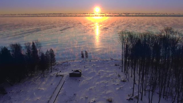 Winter sunrise over steaming, foggy Lake Michigan, aerial view.