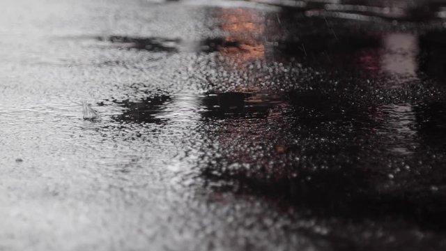 Rain hitting blacktop pavement in the city