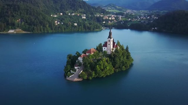 Aerial pan right sunrise island church on lake bled sunny day