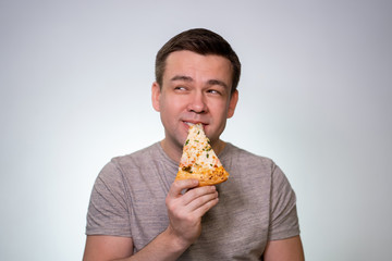 Delicious. Man bites and eats a slice of pizza. 