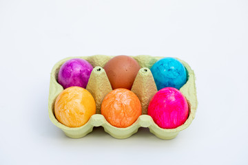 egg box with five coloured and one white egg stands on a white base