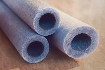 Several grey insulation for heating water pipes close-up. Industry, electrical on wood background