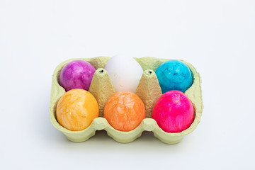 egg box with five coloured and one white egg stands on a white base