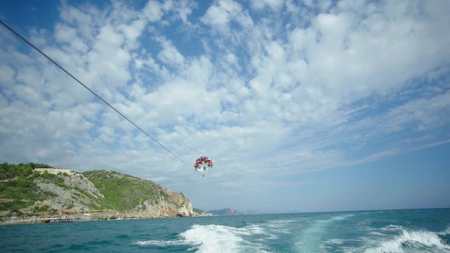 parasailing is done over the boat. parachute is flying over the sea. parachute attached to the boat.