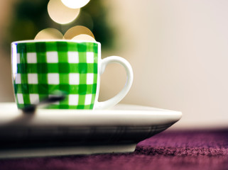 Fototapeta na wymiar a cup of coffee with green stripes on a purple fabric surface.