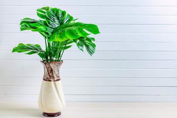 Vase with palm leaves on a white wooden background with copy space.