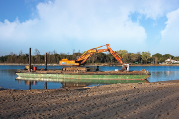 Excavator for channel dredge on a barge.
