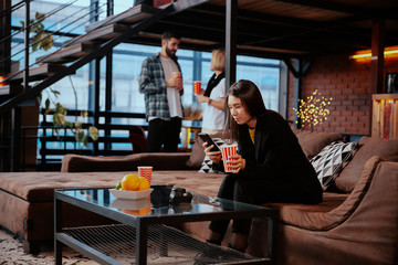 Group of students have a social project in a modern college library they sitting on the sofa socializing and drinking some drinks
