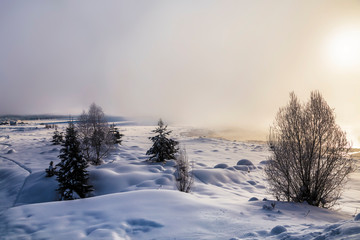 Winter landscape with fog over the river