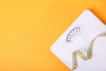 floor scales and tape measure on a colored background top view. Healthy lifestyle concept, healthy eating. Body weight control.