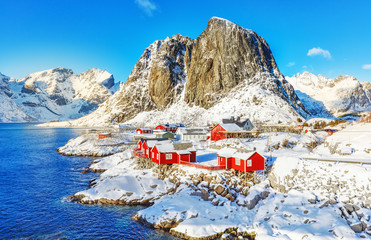 Norway, Hamnoy Scenic Viewpoint in Reine on Lofoten Islands. Red fishing houses called rorbu at Fjord bank. Amazing winter snowy landscape of Northern nature.