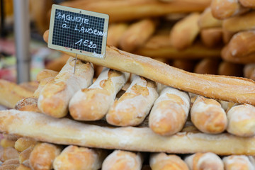 Fresh white baguettes stacked on a market stall with a price tag in euros in Saint-Palais-sur-Mer, Charente-Maritime on the southwestern coast of France