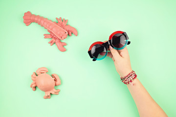 Woman hand holding stylish sunglasses. Summer holidays, vacation, summertime fashion style concept. Top view. Flat lay