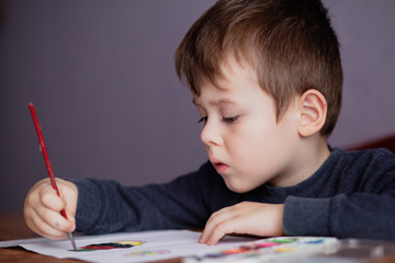 Little boy draws a brush and paint his first picture