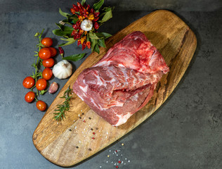 raw meat and vegetables on cutting board on dark cement background