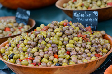 Close up image of wooden bowls with lots of mixed green, black and kalamata olives on a market stall in Saint-Palais-sur-Mer, Charente-Maritime, southwest of France