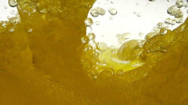 A moving background of linseed oil, which was prevented by a teaspoon. Black cumin oil does not mix with water and creates a bubble structure of air against a white background, close-up view.