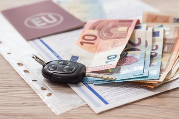 Sprzedaż samochodu. Kluczyki do samochodu leżą na stole razem z dokumentami i pieniędzmi Euro.