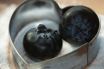 Metallic heart duet container jumbo blueberries on granulated bed of sugar free sweetener on wooden board