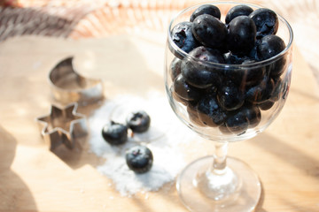 Cup of blueberries on a wooden tray next to flour fruits of the forest moon and gourmet star in Mexico